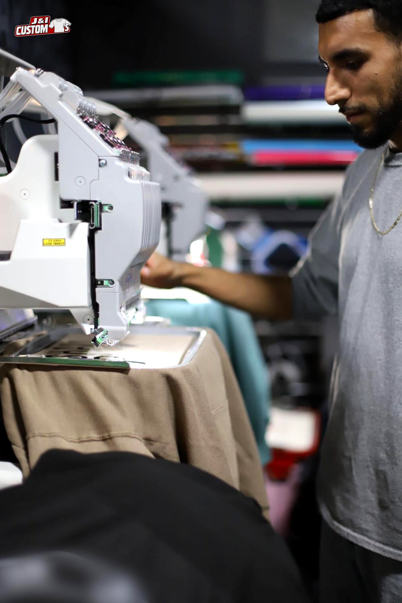 Custom apparel maker running an embroidery machine at the J And I Custom Tees studio in Lemont, IL